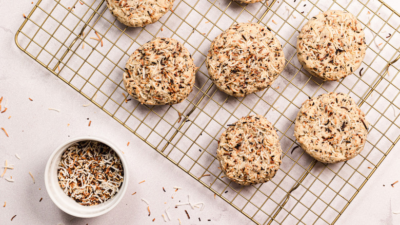 Coconut cookies on cookie rack with toasted coconut in ramekin