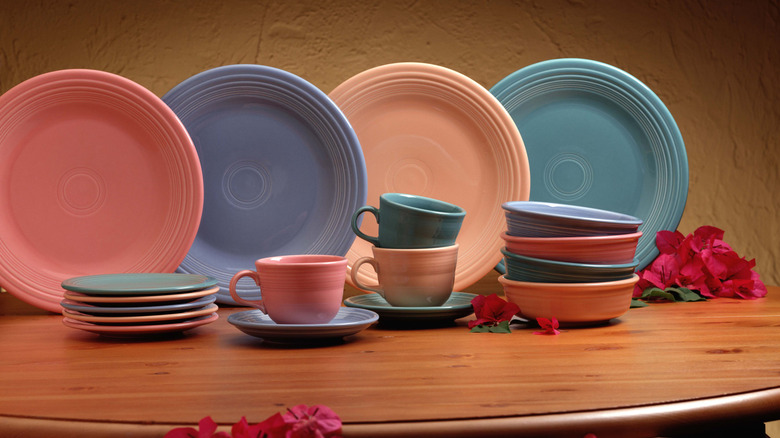 Fiestaware collection of coffee cups and plates lined on a wooden table