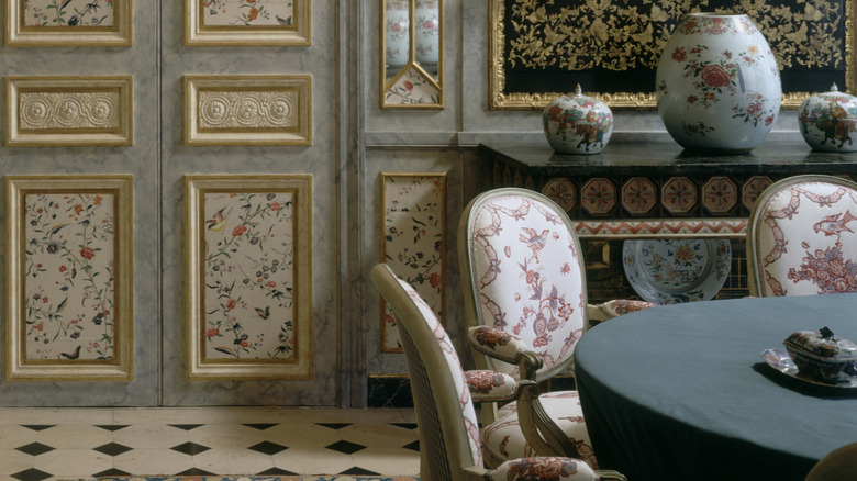 A dining room decorated with chinoiserie, including dining chairs with chinoiserie-inspired fabric.