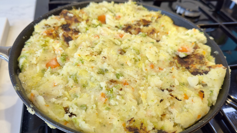 Bubble and squeak in a black frying pan cooking on a stove
