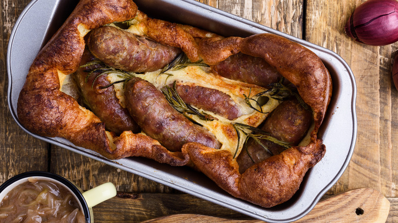 Toad in the hole in a dish on a wooden table viewed from above