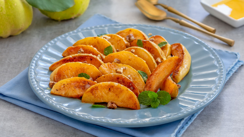 Pan-fried honey quince fritters on a plate with fresh fruits on background
