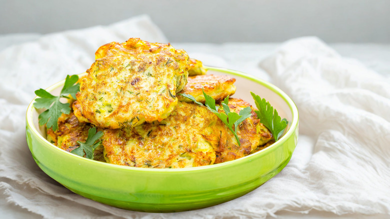 corn fritters piled in a green bowl on white tablecloth