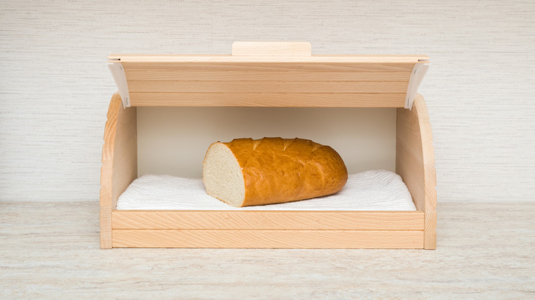 Half a loaf of bread inside an open built-in bread box in a modern kitchen