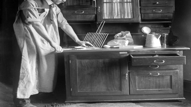 A man prepares toast on top of his Hoosier cabinet