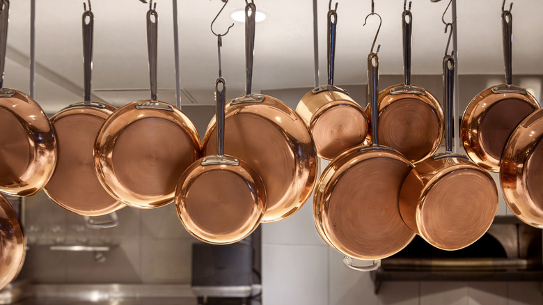 Copper pans in various sized hanging from a rack.