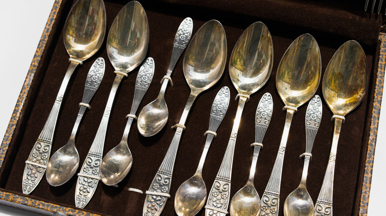 A range of silver spoons displayed inside a chest.