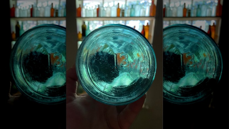 The bottom of a number 13 Mason jar in someone's hand