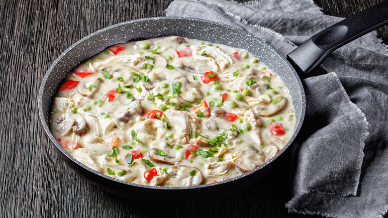 Chicken a la king in skillet, garnished with fresh herbs