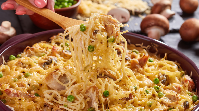 Spooning turkey tetrazzini from baking dish