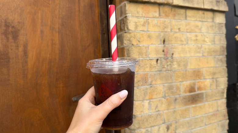 Hand holding Diet Coke slushie on the street