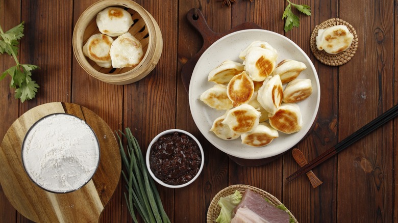 Wooden table with plate of pan fried dumplings and chopsticks