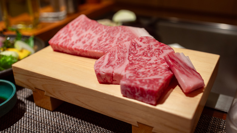 Raw Wagyu beef on a wooden tray.