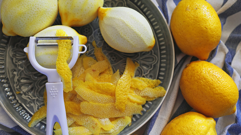 Lemon peels with peeler and plate