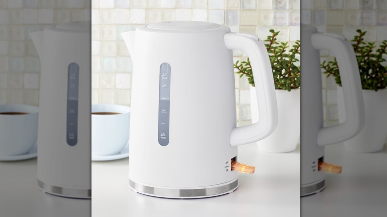 A minimalist white electric kettle in a white kitchen