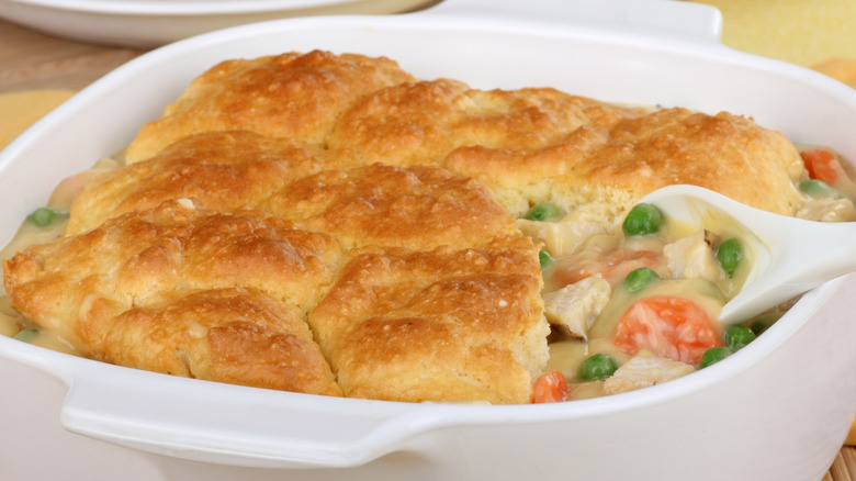 A spoon scoops out chicken pot pie from a casserole dish