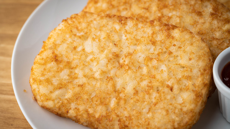 A pair of golden hash brown patties on a white plate