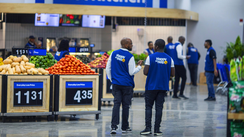 Rear view of a couple of Walmart employees in the produce department with more in the background