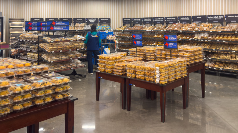 Walmart bakery section with muffins display in the foreground and employee stocking items