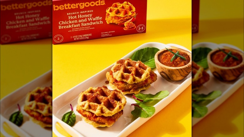 bettergoods hot honey chicken and waffle breakfast sandwiches on tray with dipping sauce and leafy greens