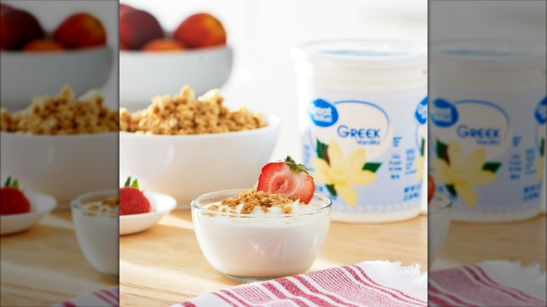 Bowl of yogurt with fruit and granola in front of Great Value greek yogurt tub