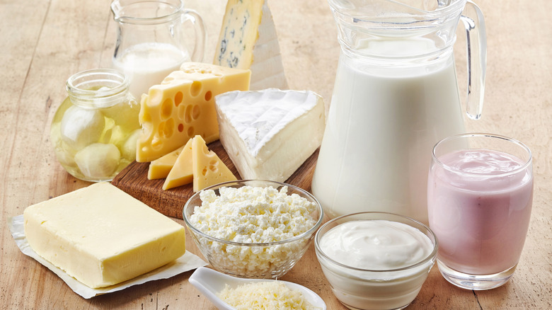 Dairy products including cheeses, yogurt, pitches of milk, and butter on pale wood floor