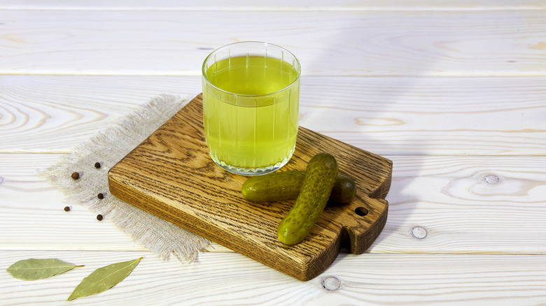 pickle juice in a glass on a board with pickles