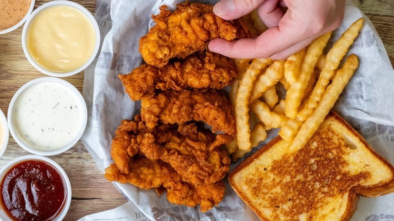 A person taking a piece of Layne's chicken