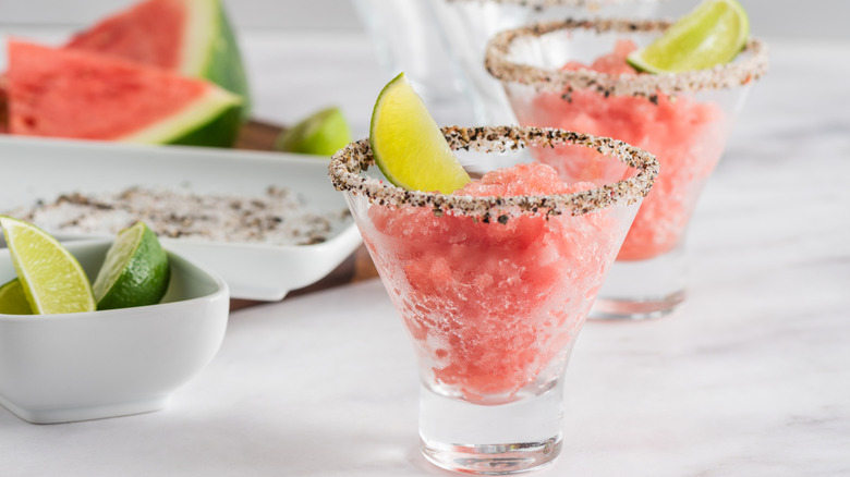 watermelon drinks with seasoned salt on rim with lime wedges