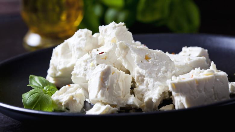 Feta broken up in a black bowl with basil