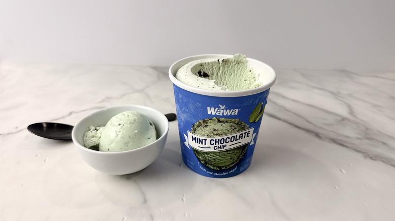 Wawa mint chocolate chip ice cream carton and scoop in a bowl with a spoon