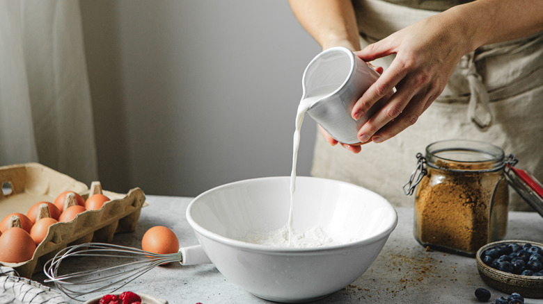 Midsection of person pouring milk into a bowl