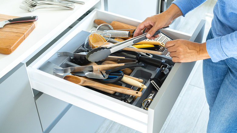 Woman puts kitchen utensils in a drawer