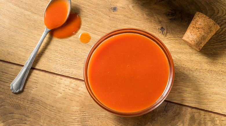 Buffalo sauce in glass bowl on wooden table