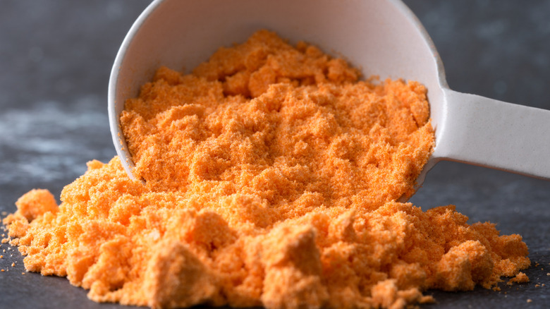 Cheese powder spilling from a white measuring cup