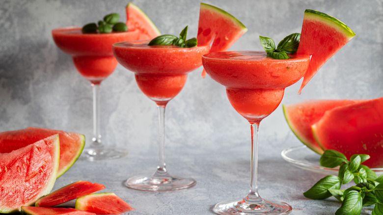 Three frozen watermelon margaritas with basil and strawberry.