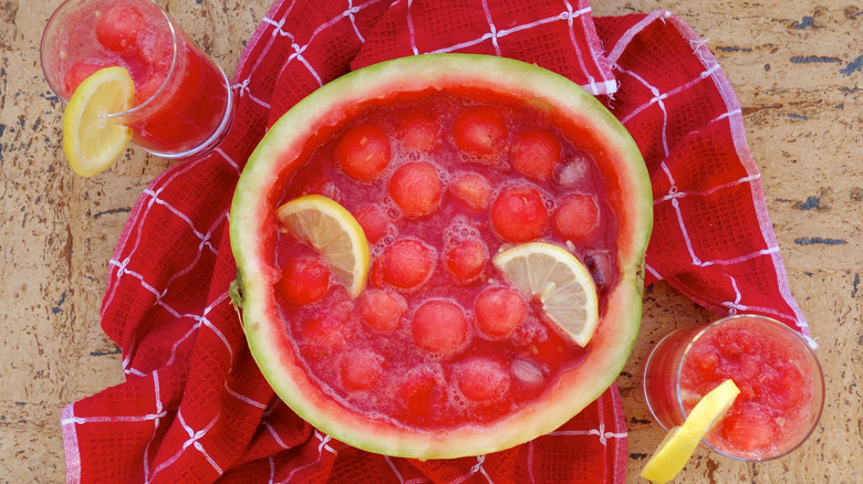 Aerial view of a watermelon punch bowl with watermelon balls next to glasses.