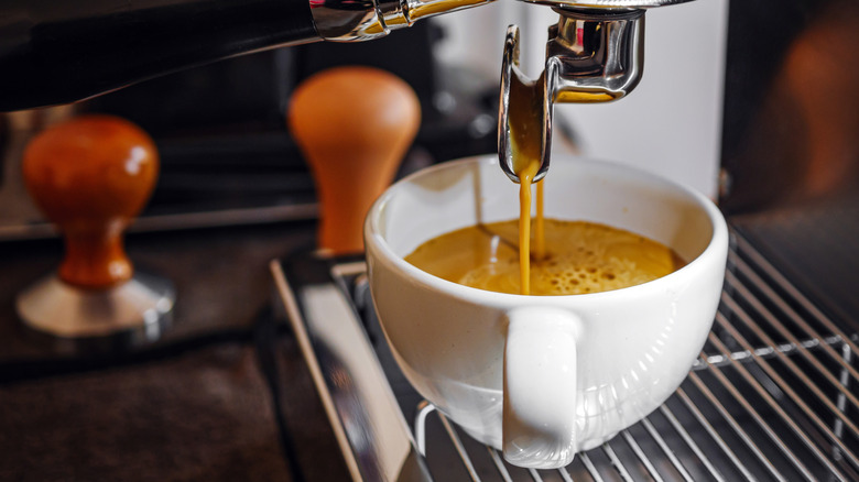 an espresso machine pulling into a white cup