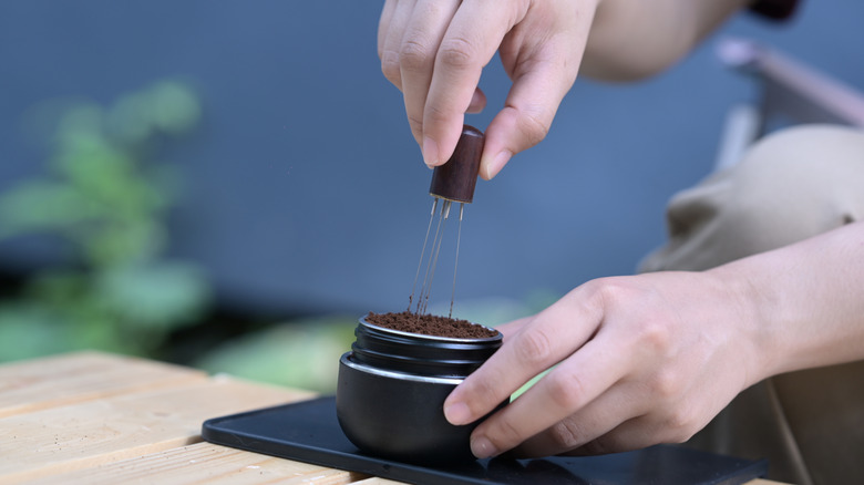 a person using a WDT tool in an espresso portafilter