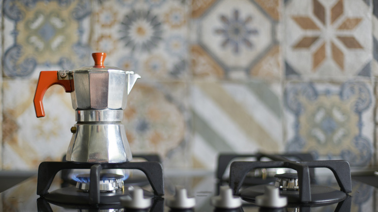 Moka pot in front of tiled backsplash