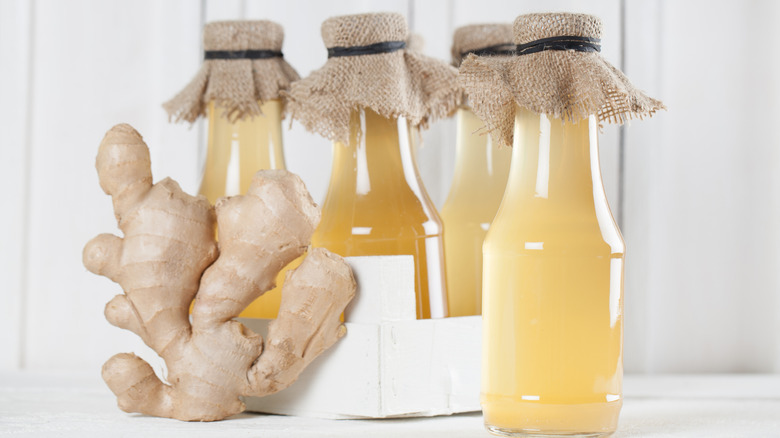 Bottles of homemade ginger syrup next to fresh ginger