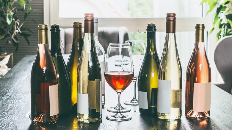 several wine bottles on table with wine glasses