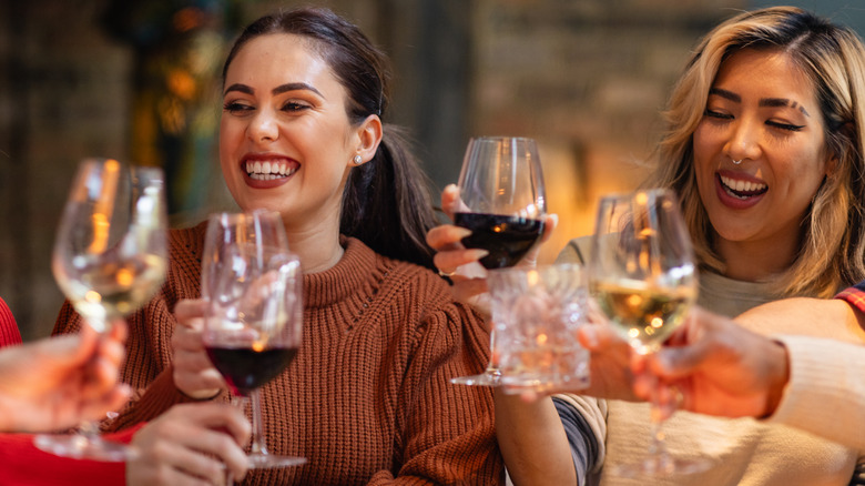friends clinking wine glasses and smiling
