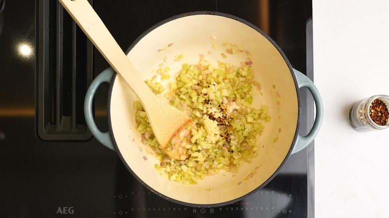 Aromatics cooking in pan with wooden spoon