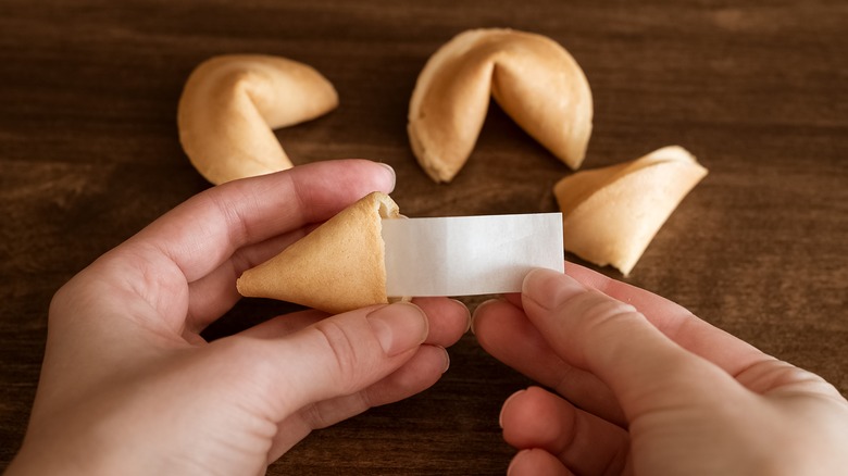 hand holding fortune cookie slip in cookie