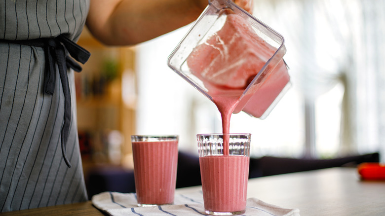 woman pouring milkshake into two glasses