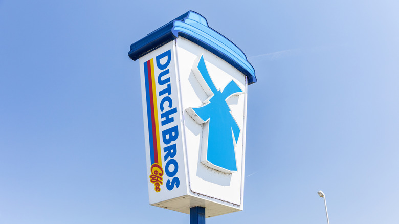 Large Dutch Bros sign in the shape of a to-go coffee mug, featuring a large blue windmill