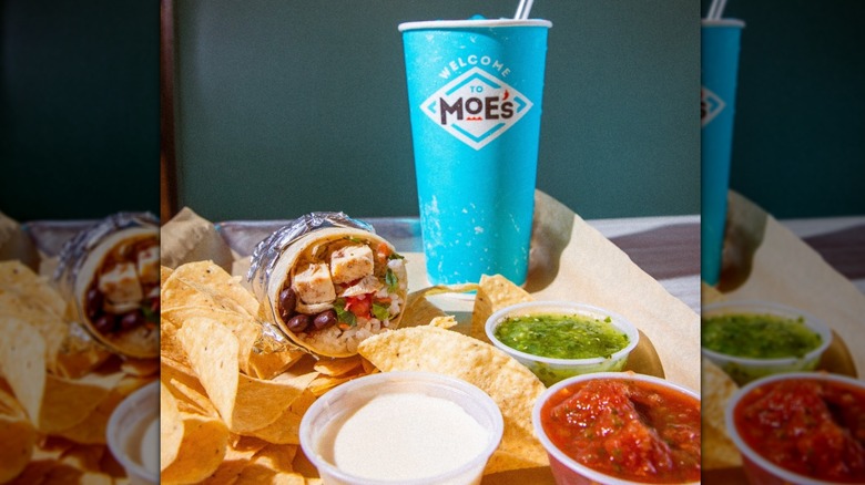 View of Moe's chicken burrito, chips, salsa, and queso on a tray