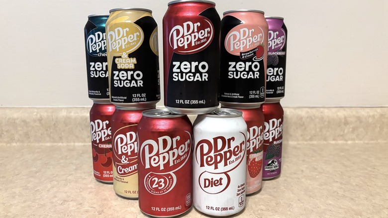 A variety of Dr Pepper flavors in can on a neutral background.