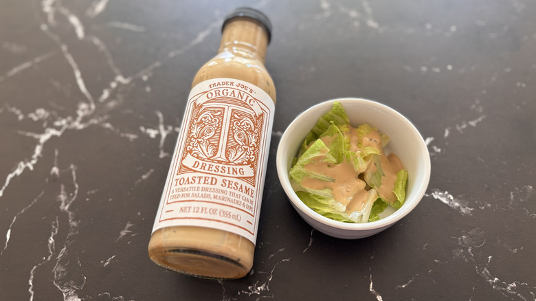 Trader Joe's toasted sesame dressing bottle next to small bowl of salad